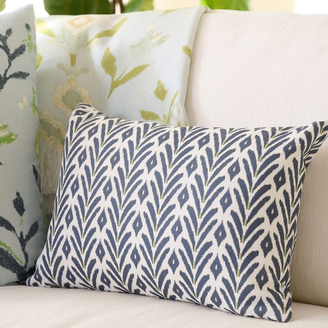 Laura Park decorative 14x36 throw pillow with an ikat-inspired motif in deep navy with subtle green accents styled on a light colored couch with a petal garden aqua throw blanket and a petal garden navy pillow. 