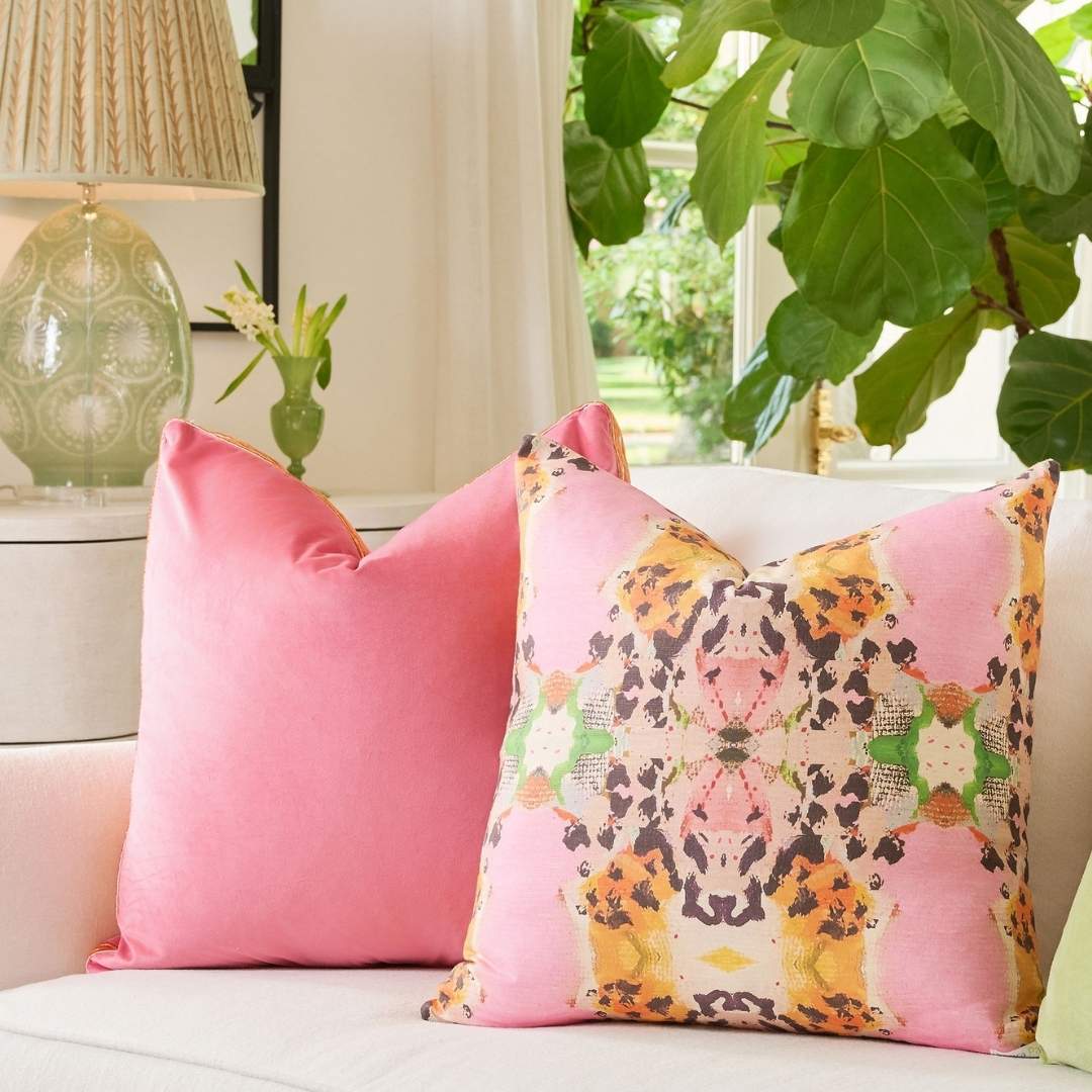Pink velvet embroidered pillow with orange accents paired on a couch with a Laura Park Tiger Lily Decorative pillow. 