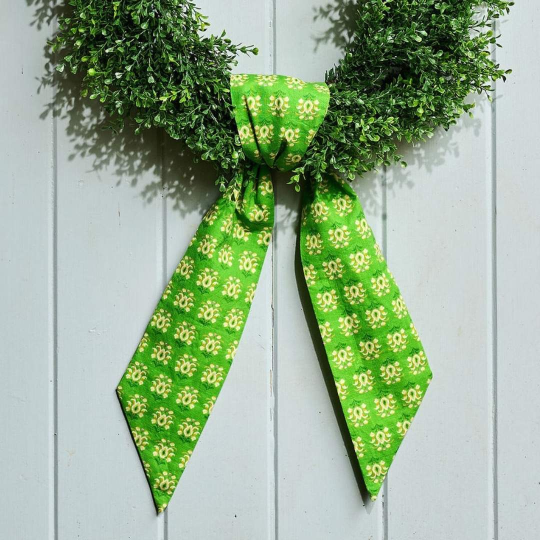Green wreath with a matching green patterned wreath sash in Laura Park's signature rosemary meadow artful painted design on a grey door. 