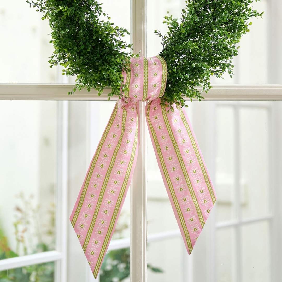Hand painted design, Pink and green floral striped sash by Laura Park seen on a green wreath on a glass paned door. 
