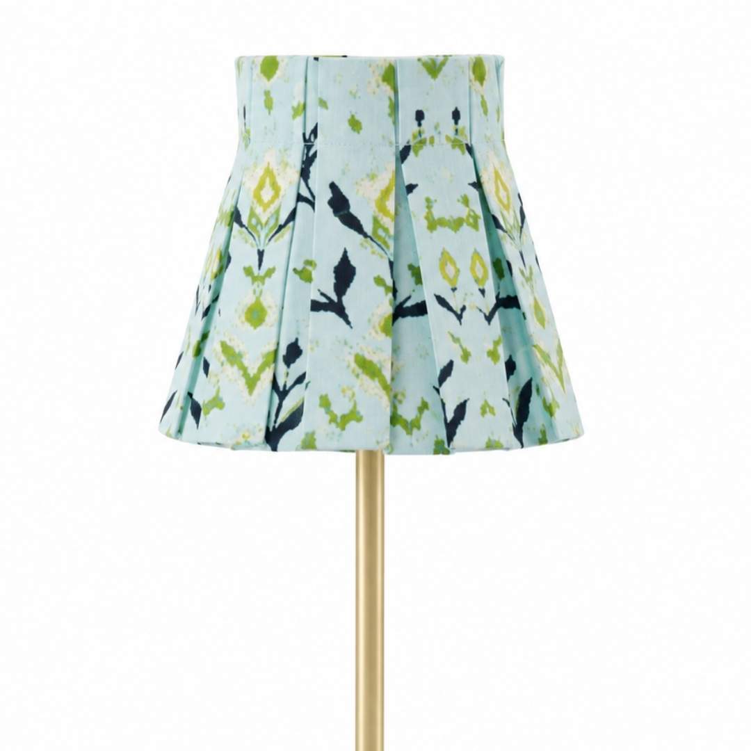Pleated and hand painted green, navy, and light blue lampshade slipcover in petal garden navy by laura park, styled on a gold lamp perfect for bedside tables, entryways, and more. 