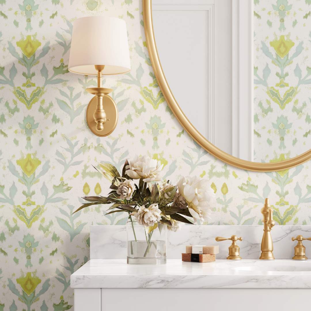 Laura Park's Petal Garden Linen Peel and Stick wallpaper styled in a bathroom/powder room with marble and gold accents. Wallpaper has floral accents of blue and green on an off white, linen colored background. 