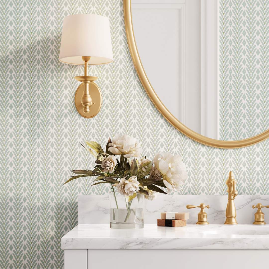 Petite Frond Blue Peel and Stick Wallpaper by Laura Park featuring a bathrooom or powder room with marble countertops, gold accents, an oval mirror, and a wall sconce — bedroom and accent wall decor.