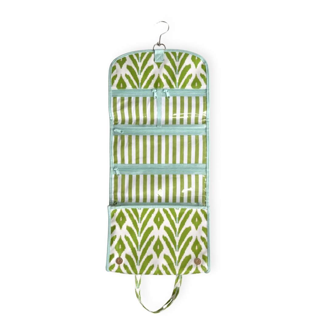 Green and white patterned travel hanging organizer bag with a wipeable inside lining and striped pockets with a blue outside lining and zipper. 