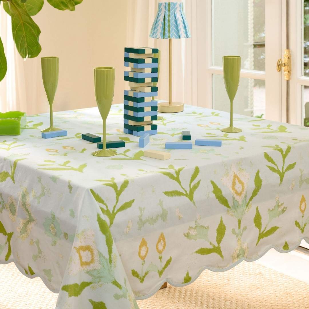 Square scalloped game tablecloth on a white table with petal garden aqua pattern by Laura Park for a card table, game table, mahjong table set up to play a game with green acrylic champagne flutes on the table. 