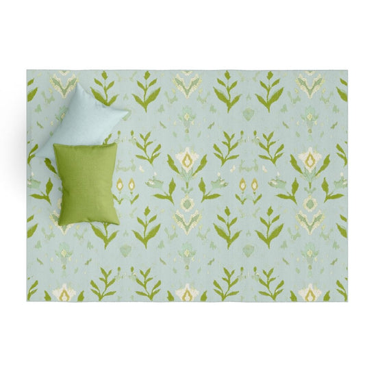 Laura Park's Signature painted pattern, petal garden aqua on a floor mat rug for indoor use in kitchen, bathroom, entry room, mud room, bedroom. Styled with a blue and green pillow. 